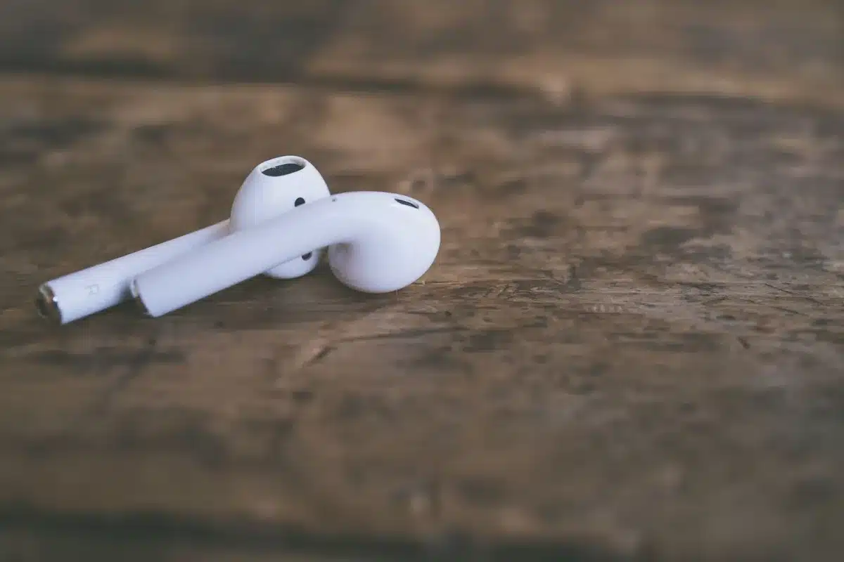 Dual earbud silhouettes side-by-side with subtle LED indicator glowing, minimalist technical scene, dark background with soft blue accent lighting