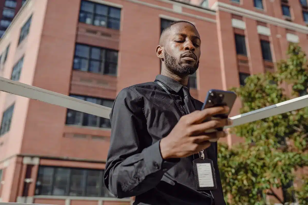 Forensic technician at workstation with mobile device connected to extraction hardware, multiple monitors displaying data analysis interfaces and encrypted file structures
