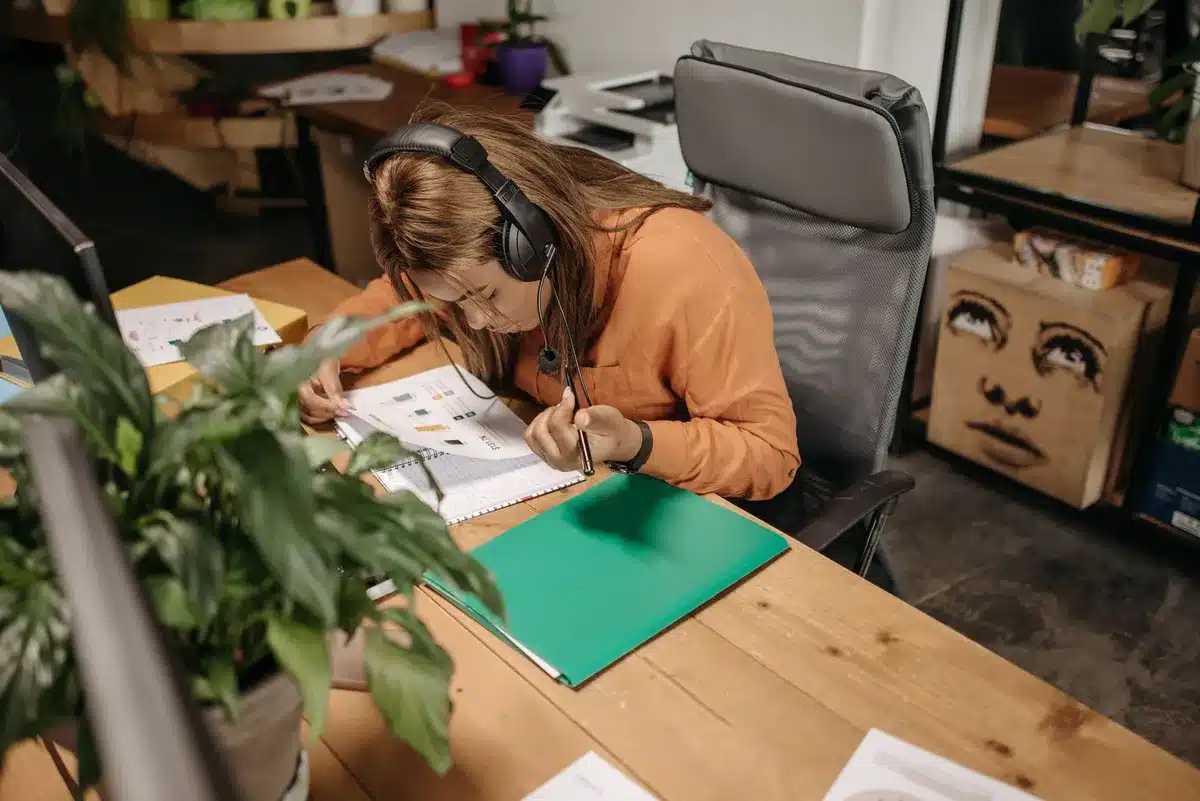 Over-ear headphones with titanium drivers resting on a desk, surrounded by study materials and a laptop, warm lighting highlighting the cushioned ear cups and minimalist design aesthetic