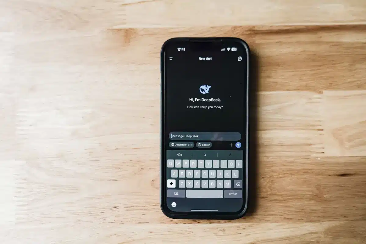 Sleek foldable smartphone in open position on minimalist desk, internal screen glowing, thin hinge visible, modern device aesthetic