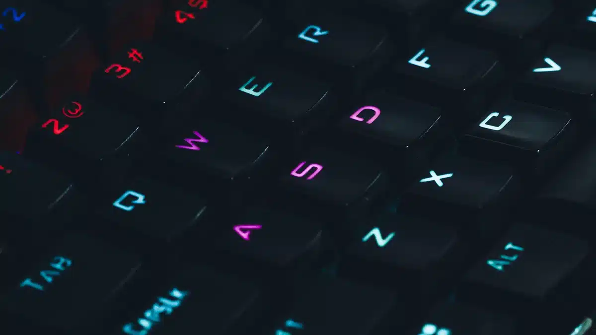 Close-up of gaming laptop keyboard with RGB backlighting, metallic chassis detail, and a hint of the OLED display edge showing color, shallow depth of field&mdash;craftsmanship and performance.