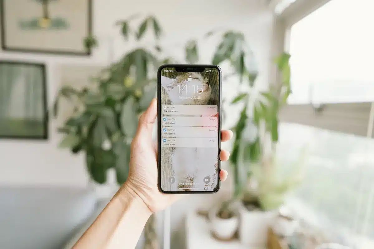 Close-up of hands holding an iPhone displaying job application notifications and alerts, with a modern minimalist interface visible
