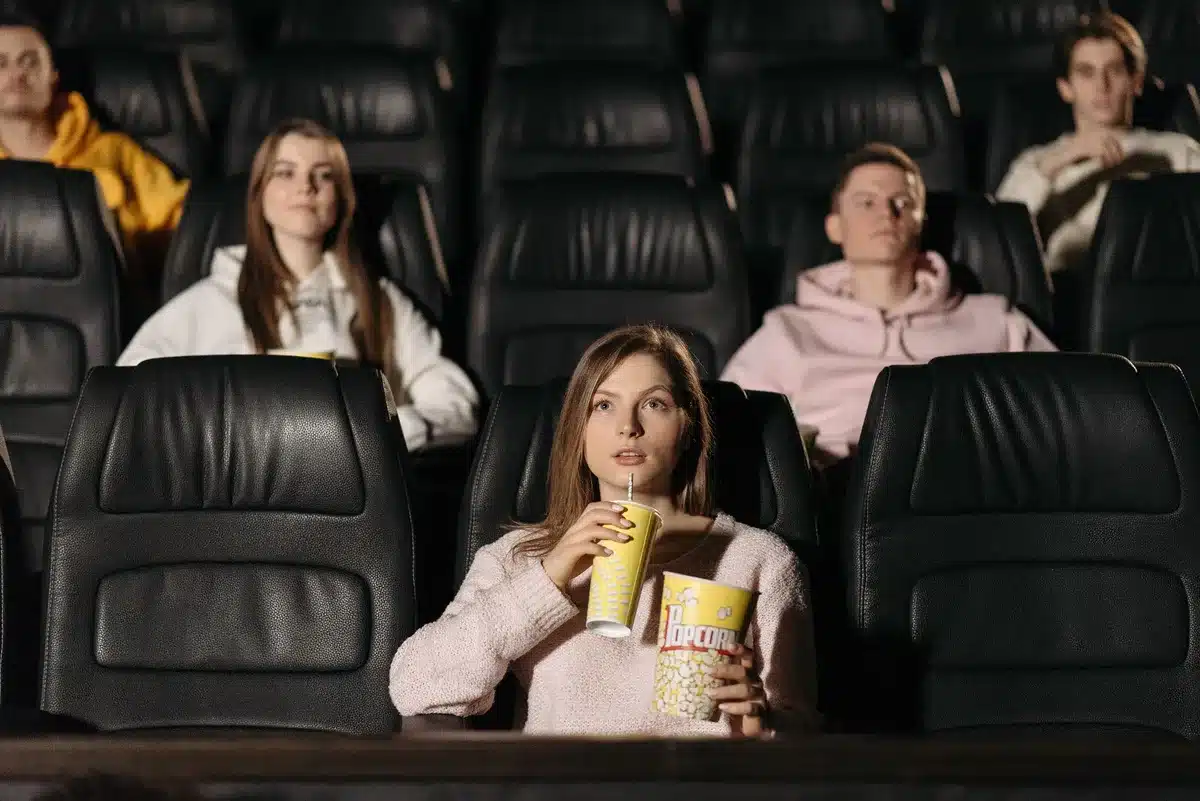 Público en una sala de cine viendo una película de superhéroes en la pantalla grande