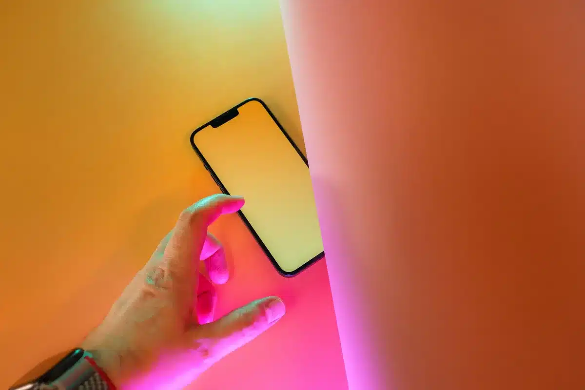 Mid-range phone displaying vibrant AMOLED screen in bright sunlight, tilted angle showing display clarity and brightness, premium materials visible