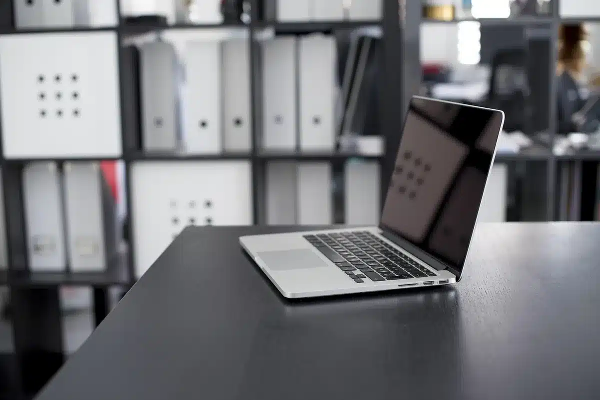 A long wooden desk top with embedded charging hardware visible through a small cutaway; no people visible, cables tucked away and a glowing spot where a phone would sit