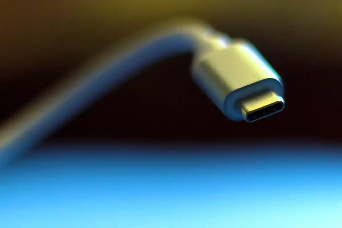 Manos anónimas sujetando un gamepad modular junto a un cable USB-C y un dongle inalámbrico