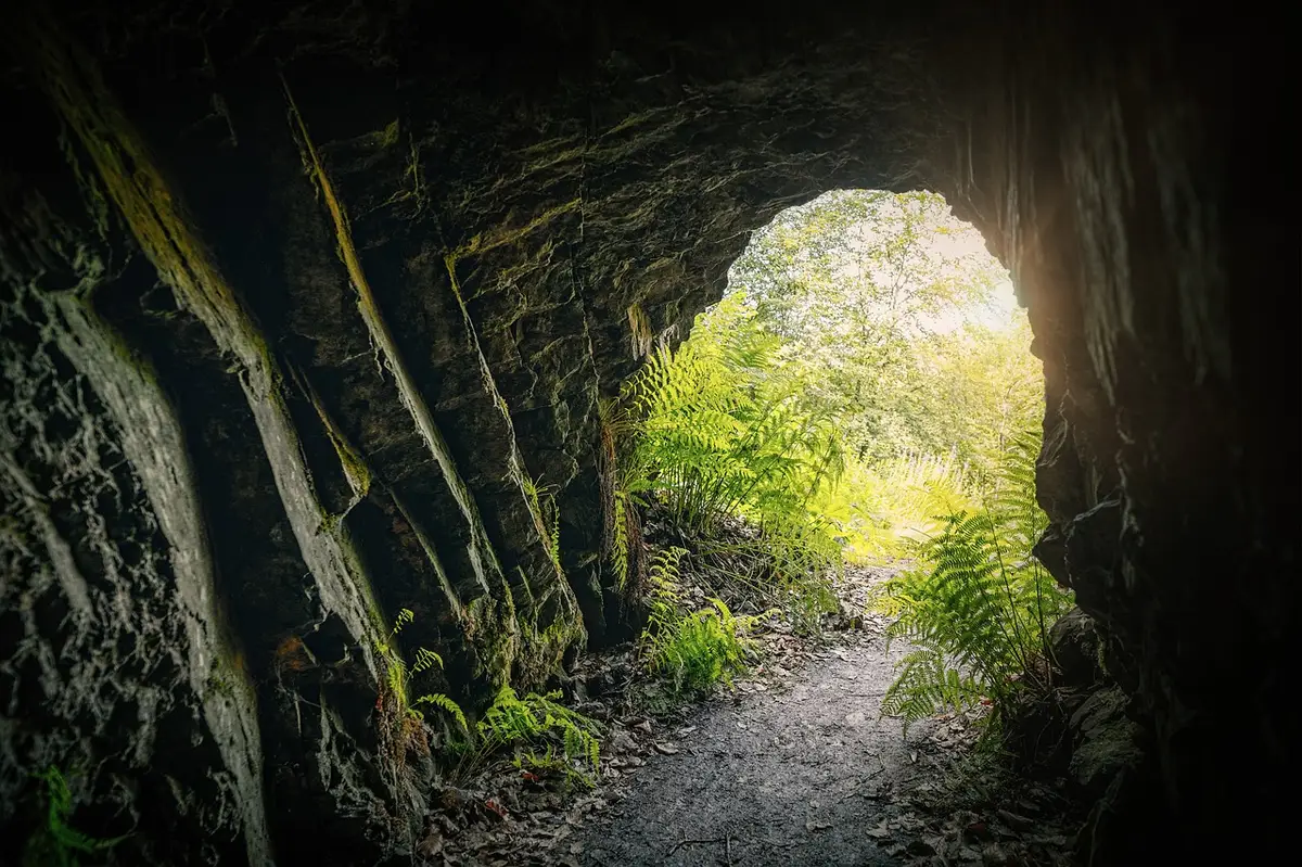 Underground tunnel entrance with stone archway and glowing pathway leading into darkness, representing the unlocked tunnel system
