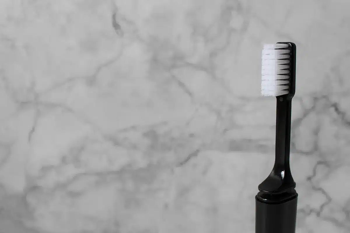 Cepillo suave y productos para limpiar ante sobre una superficie neutra
