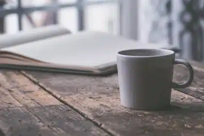 Manos sosteniendo botines, mocasines y zapatillas en una mesa con etiquetas de descuento desenfocadas
