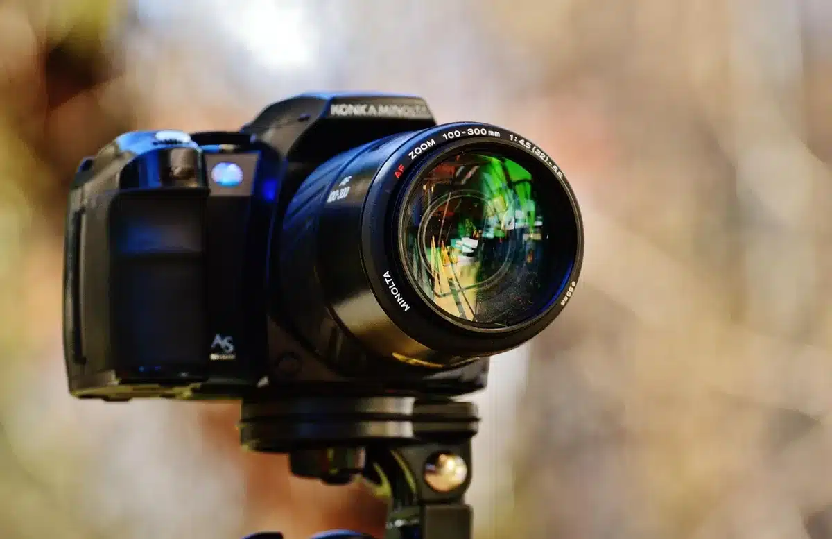 Cámara DSLR montada en trípode sobre un mirador urbano, enfocada hacia las luces de la ciudad nocturna, con cables disparador remoto visibles