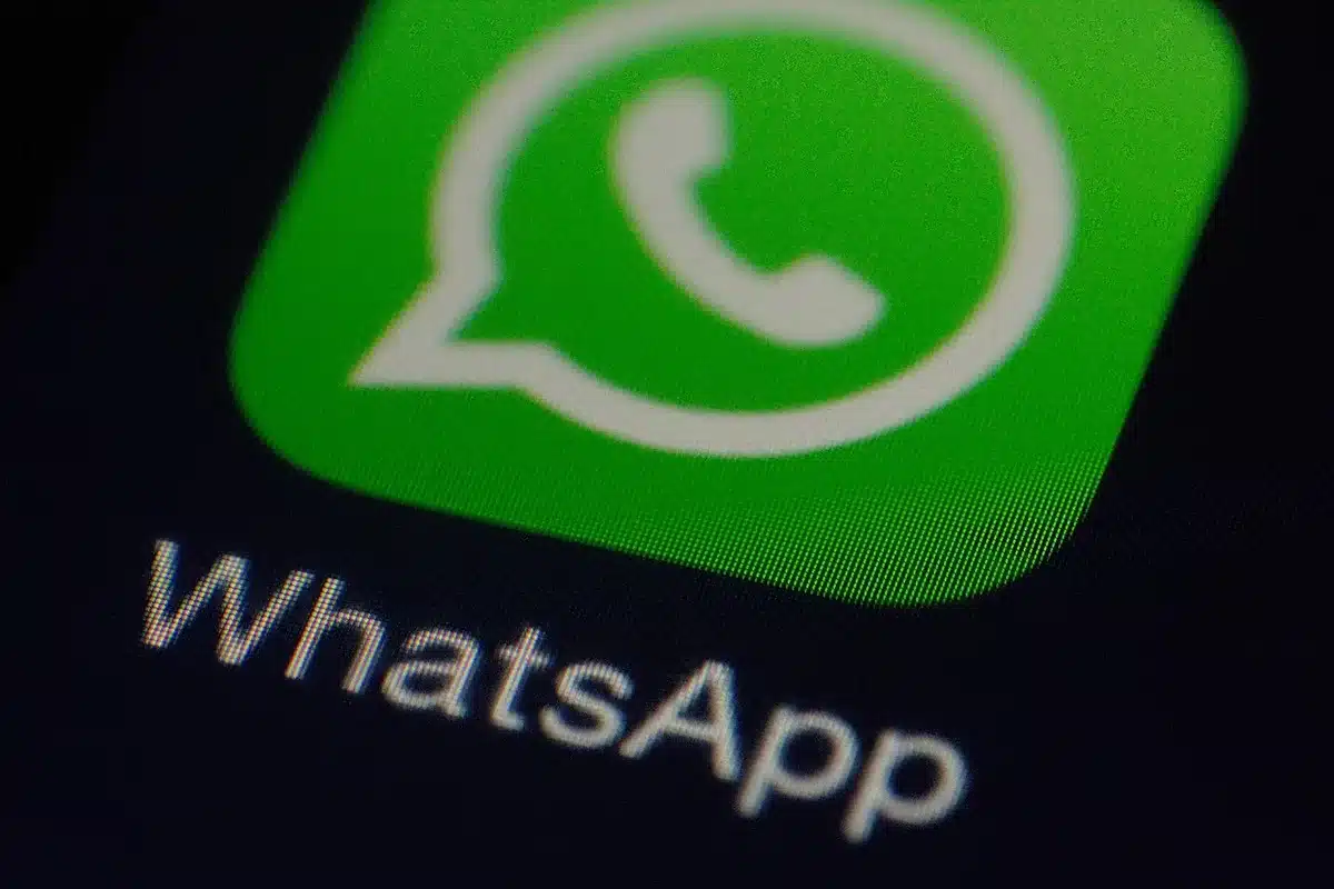 A smartphone screen displaying WhatsApp settings menu with focus on the media visibility option, clean interface with white and green elements, user adjusting privacy controls