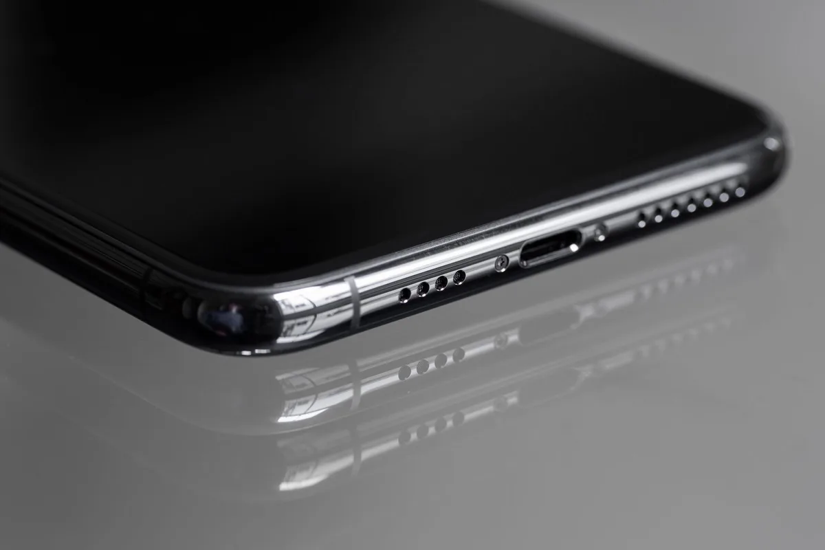 A large unbranded smartphone lying on a wooden table with a visible battery icon overlay graphic hovering above it, no logos or text