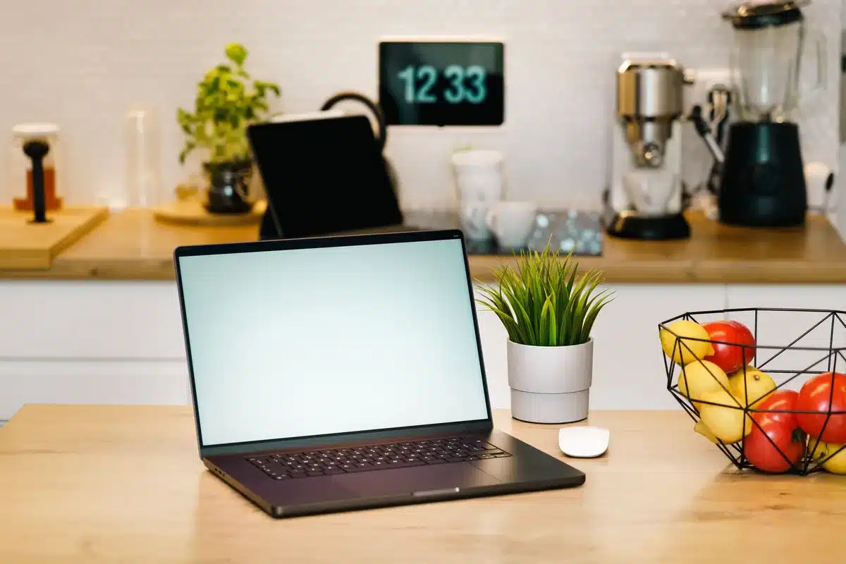 A compact 7-inch smart display on a tabletop next to a ceramic mug and a notepad, no branding visible