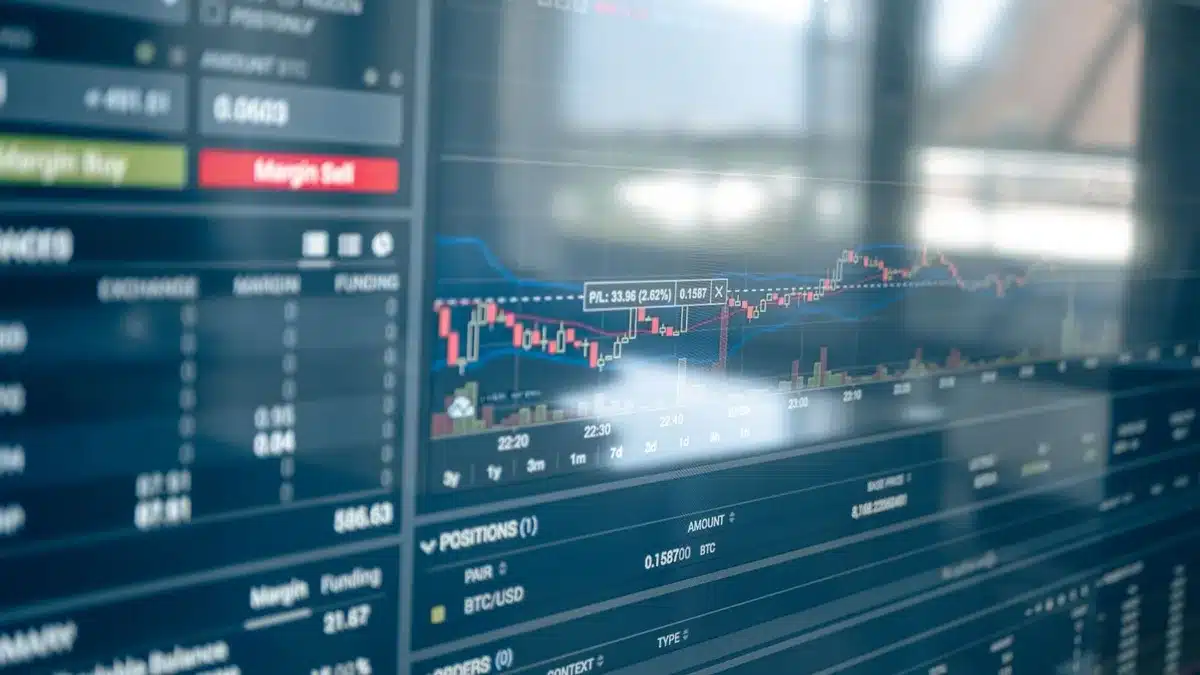 anonymous hands typing on laptop with financial charts visible
