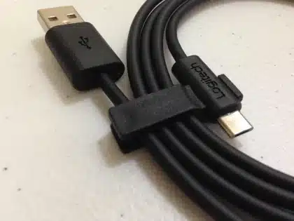 Consola portátil genérica sobre mesa con manos anónimas y accesorios