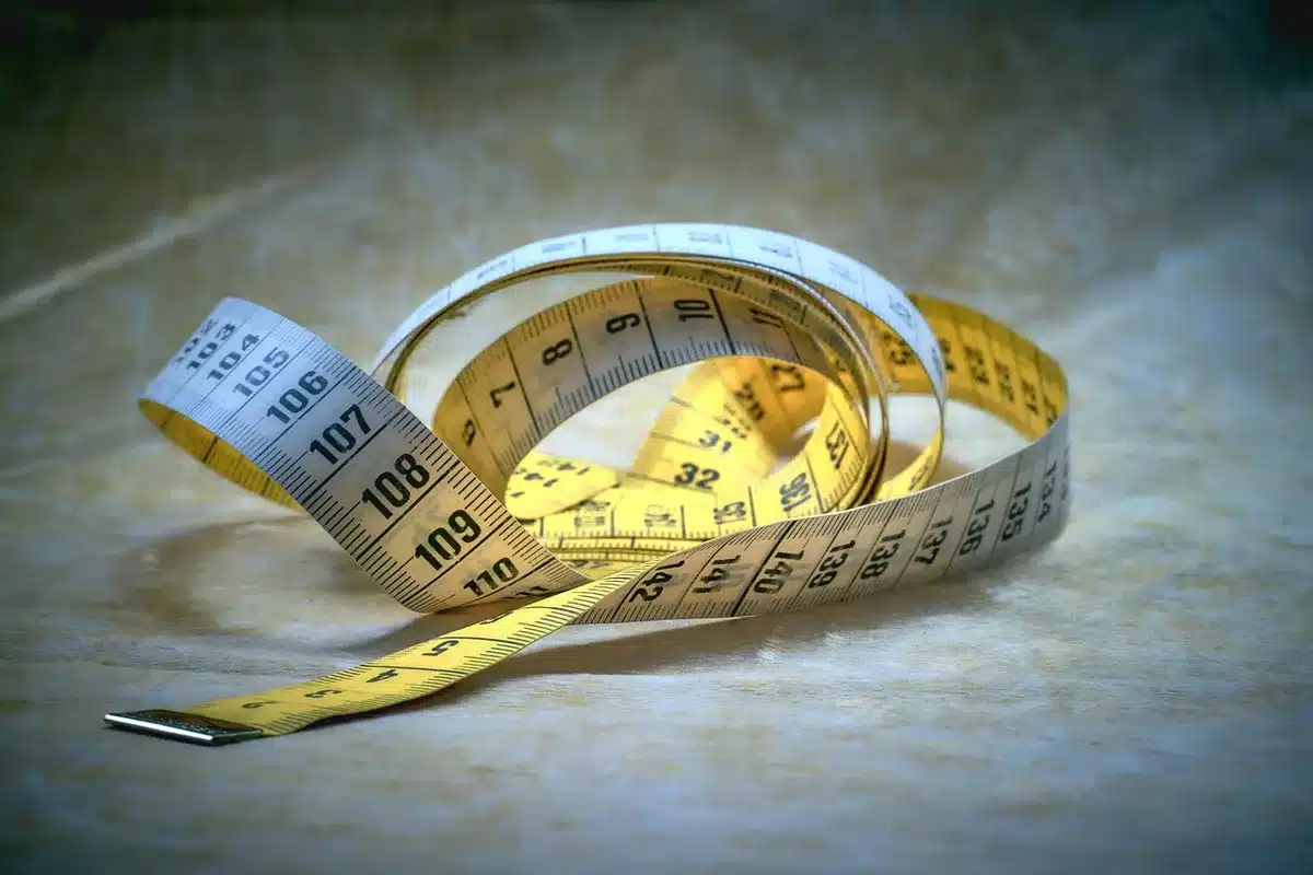 Close shot of a tape measure across a sofa to a blank wall where a TV would hang, anonymous scene