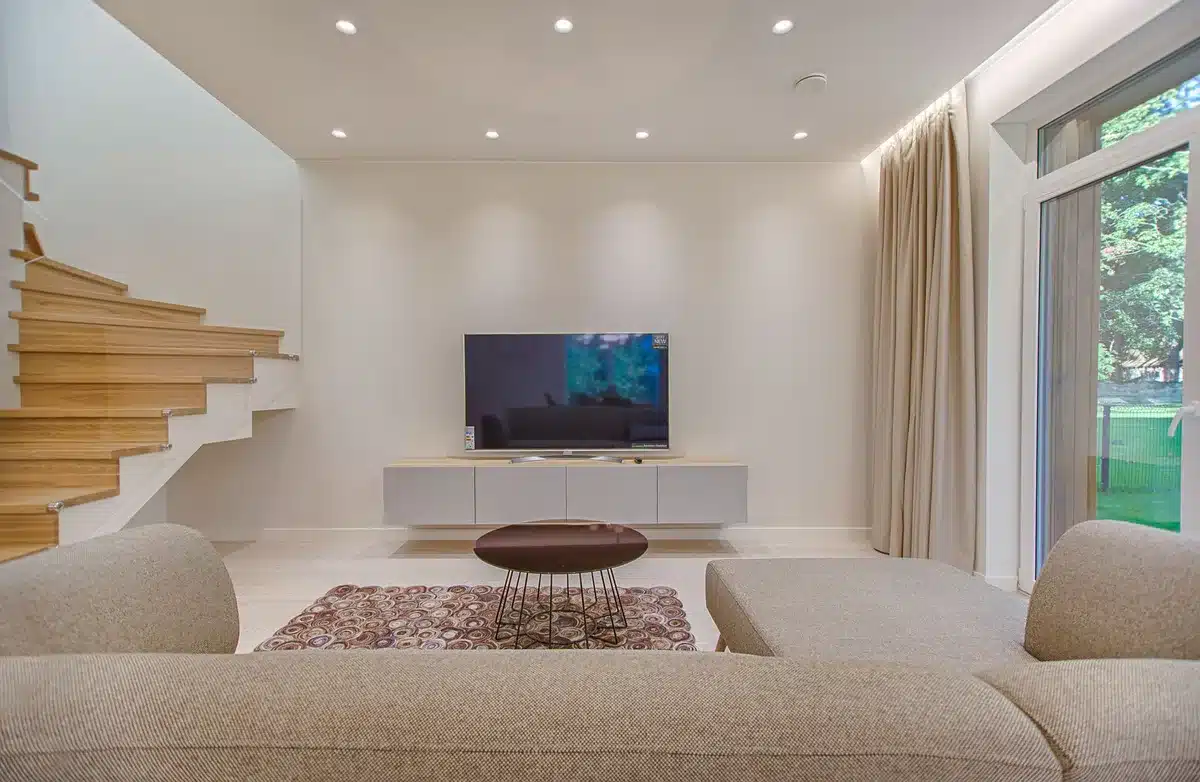 Empty living room with large unbranded TV on stand, soft daylight through window, no people