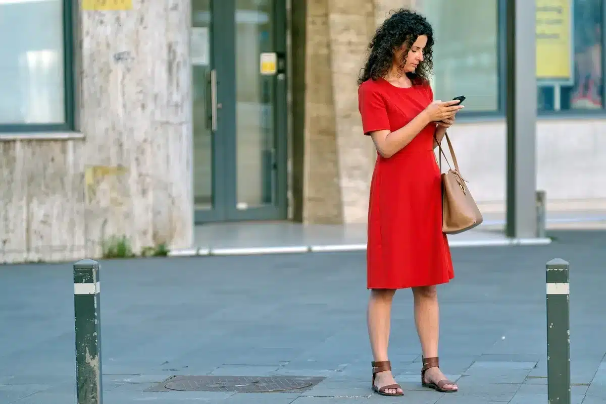anonymous hands holding an unlocked iPhone near a wall-mounted smart display