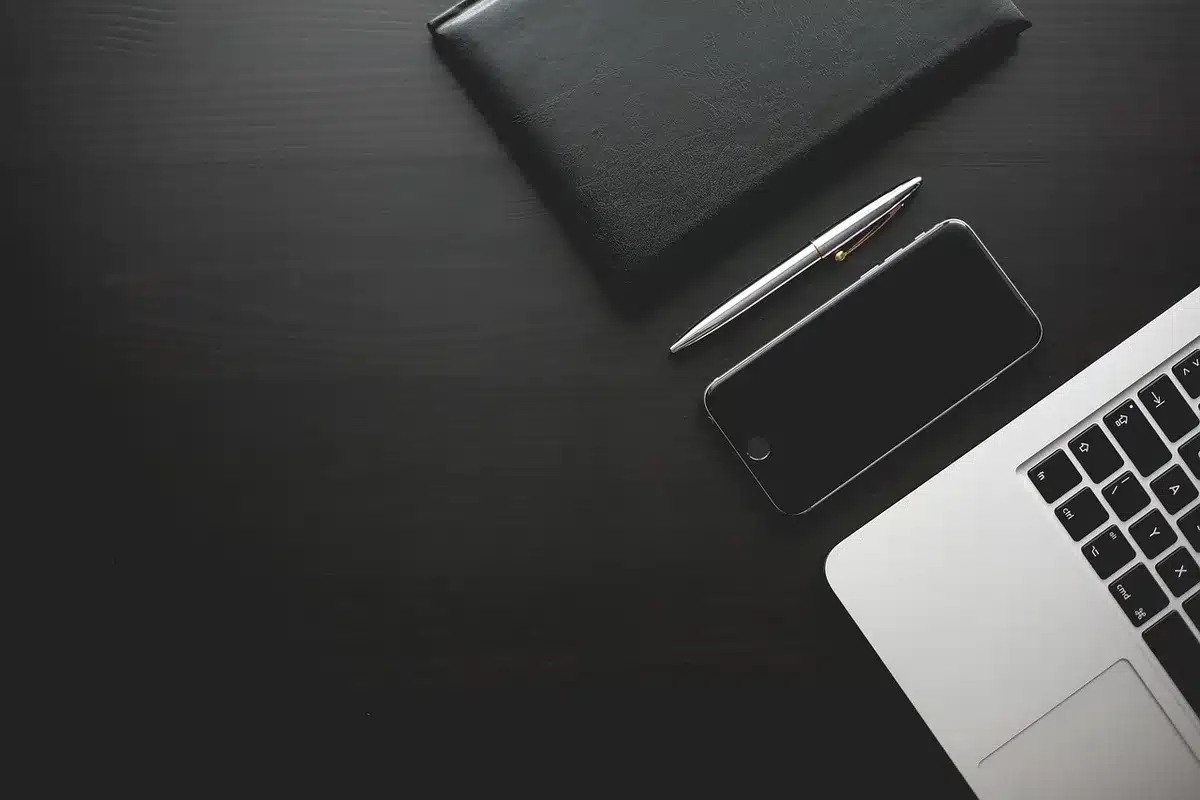An anonymous folded smartphone on a simple table, both screens visible and turned on showing abstract app tiles, soft daylight from window