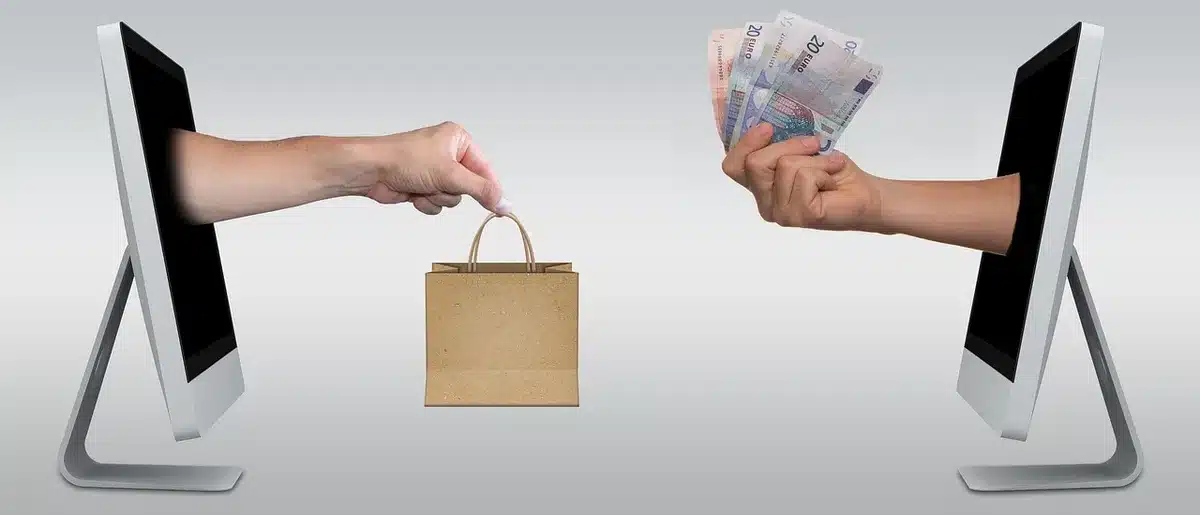 Close view of two anonymous hands preparing an online purchase on a laptop showing a generic product page, no visible brand or text