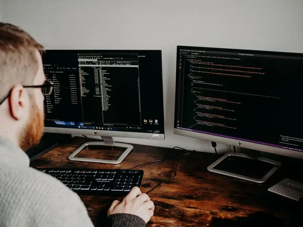 Empty developer workstation with a MacBook showing blurred code lines and a notebook beside it