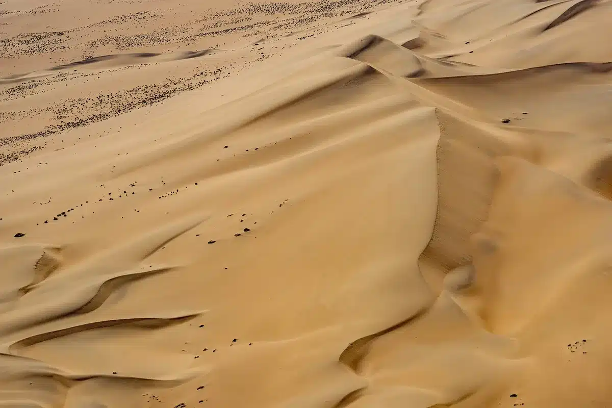 Cúpula blanca de diseño junto a piscina y dunas rojizas en un entorno remoto
