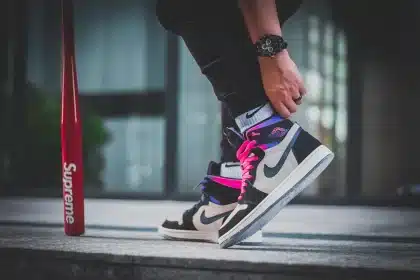Zapatillas, chaqueta y pantalones deportivos doblados sobre una mesa, con manos anónimas revisando tallas