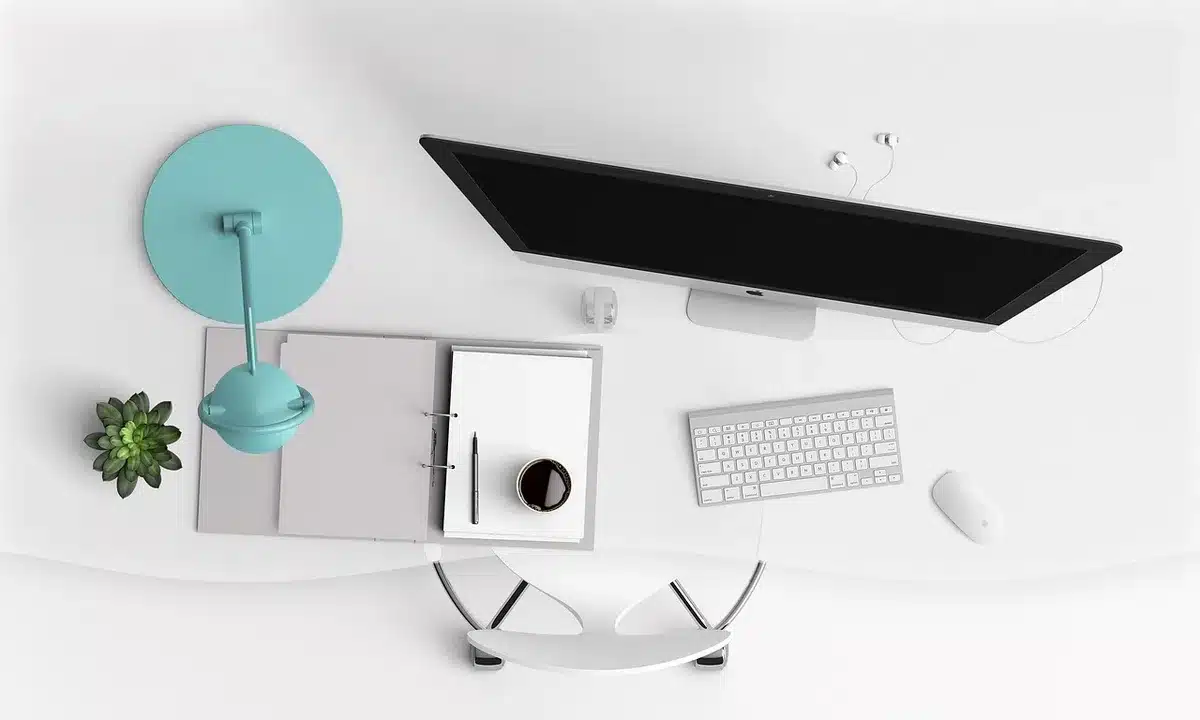 Portátil genérico cerrado junto a mochila y ratón sobre mesa de estudio