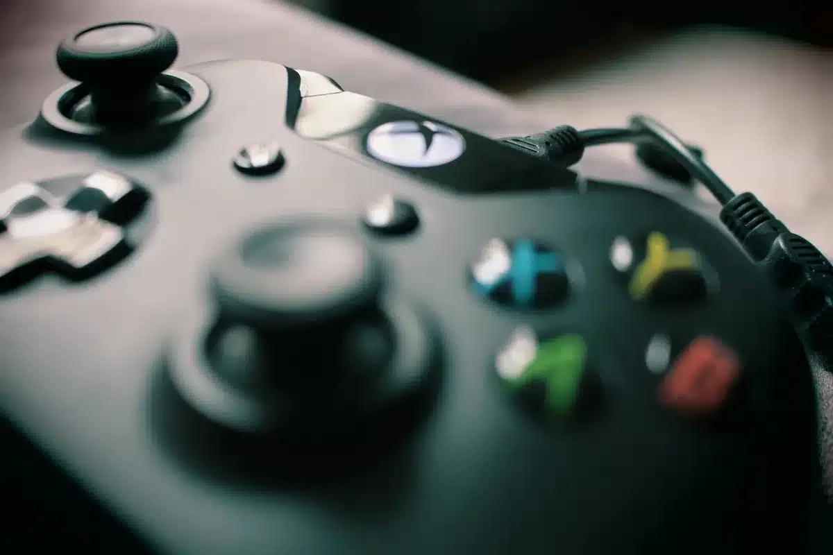 empty living room with a modern unbranded console on a TV stand, an anonymous game controller on the couch, soft ambient light suggesting evening play