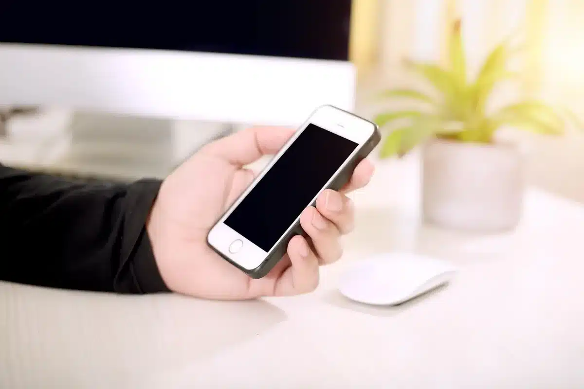 anonymous hands holding a smartphone showing a blank app screen, crowded tram in background out of focus