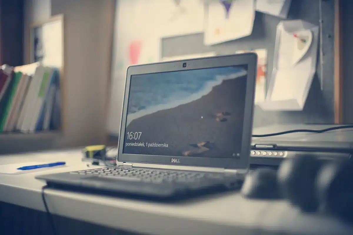 empty laptop on desk with OS update progress visible on screen; anonymous workspace, soft daylight
